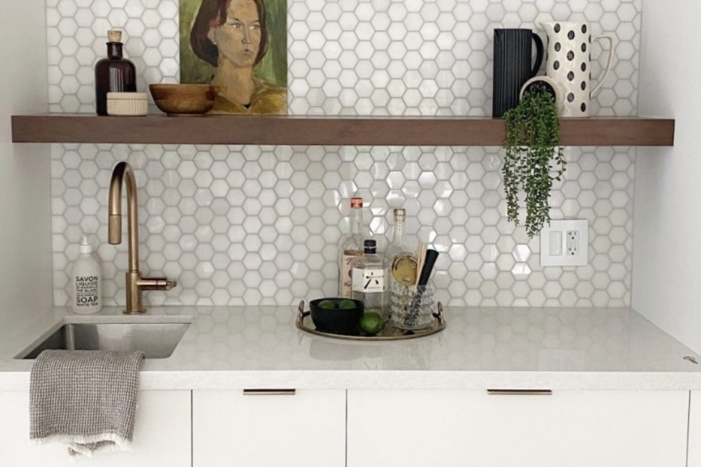 A small kitchen bar area with clean white countertops and clean white hexagonal tile backsplash.