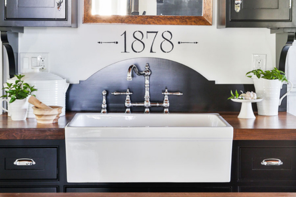 9. A sleek porcelain farmhouse sink in a historic renovated kitchen, complete with silver faucets and hardwood counters.
