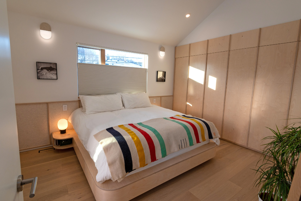 A simple Scandinavian-style bedroom, constructed using lots of wood and sparsely decorated.