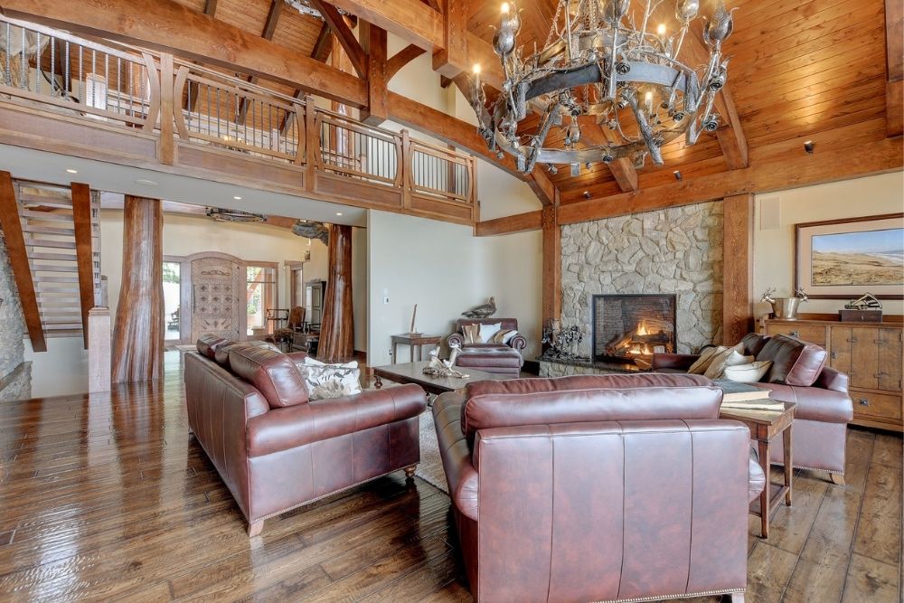 A luxury kitchen with red leather couches, a stone fireplace and hardwood floors.