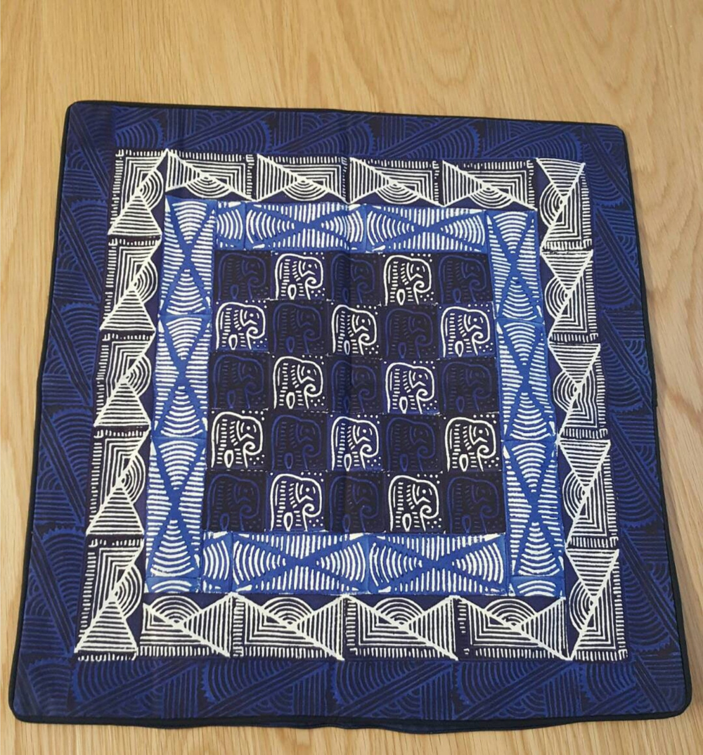 A traditional patterned Sadza batik cushion cover, featuring an African elephant pattern on a deep indigo background.