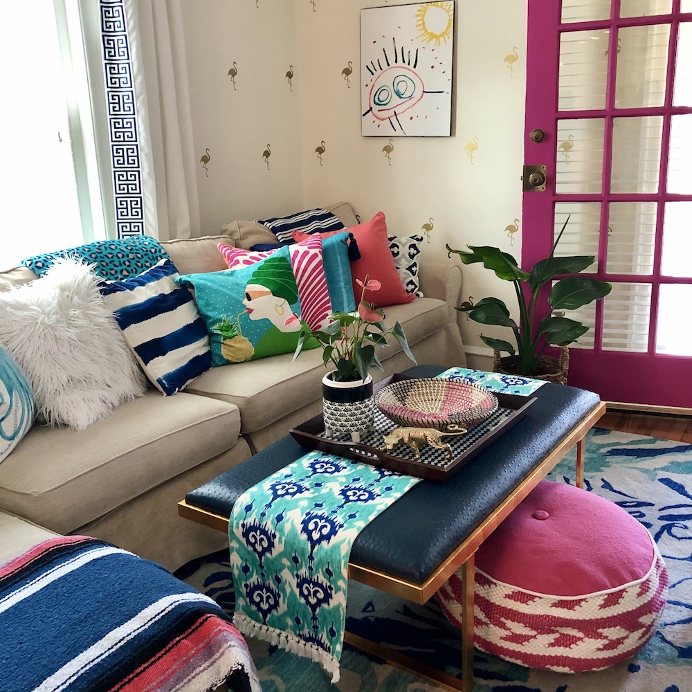 Colourful patterned pillows on sofa with hot pink French door
