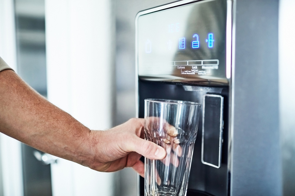 Person getting a glass of water from a fridge dispenser