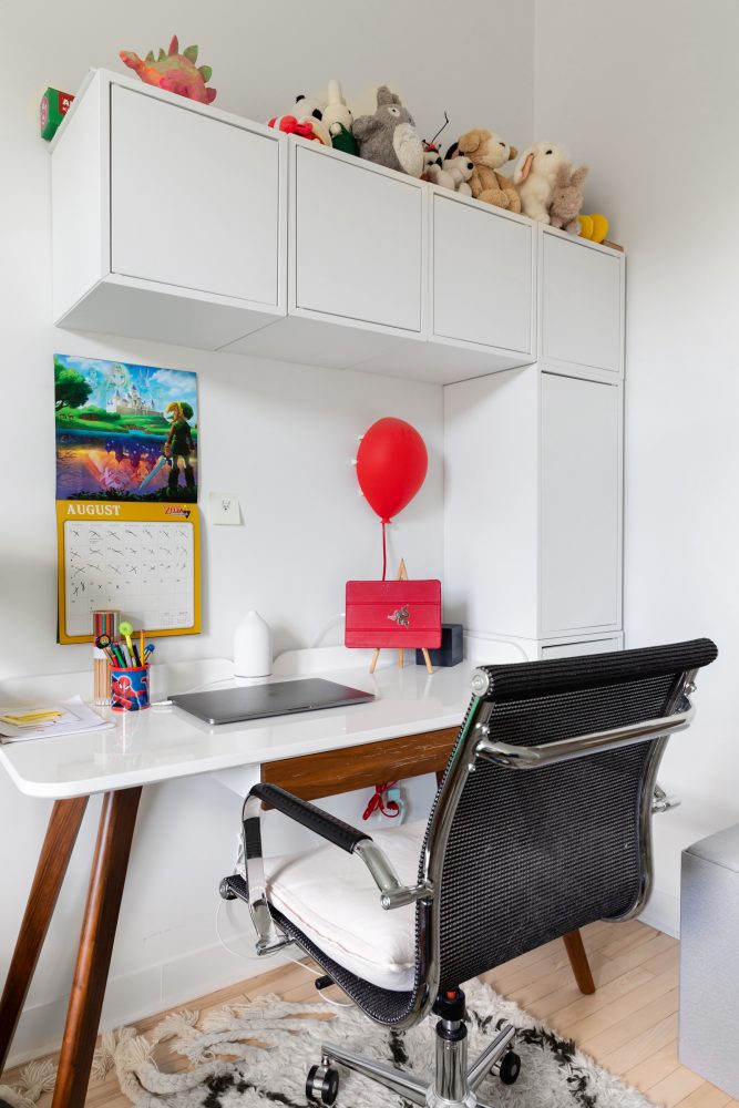 White kids’ desk with cabinets above desk and colourful calendar on wall