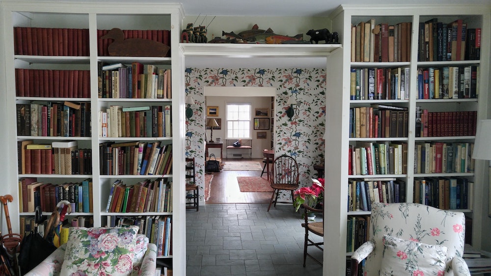 Library with floral wallpaper and wingback chairs