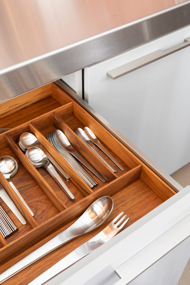 open kitchen drawer with silver utensils in dividers