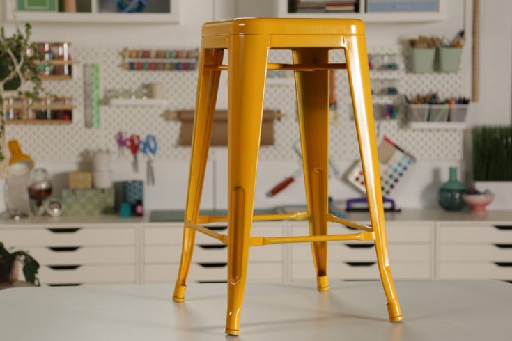 A metal stool spray-painted bold orange all over.