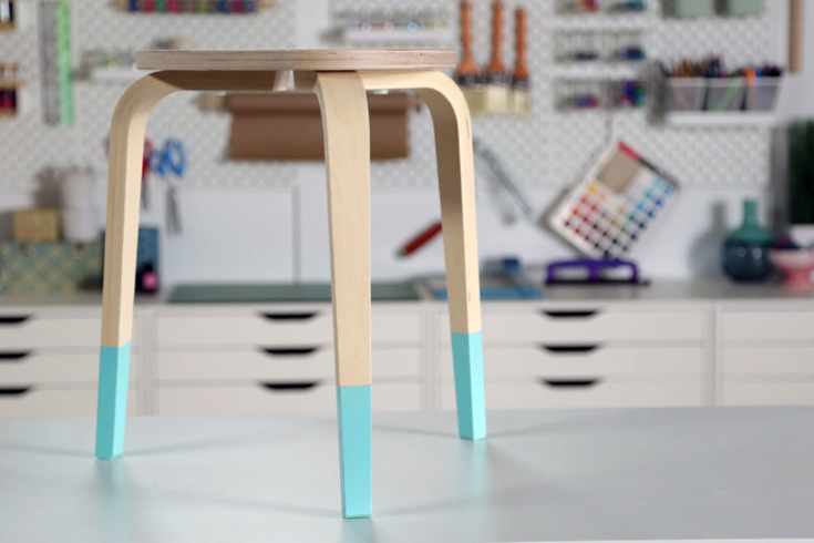 The three-legged wooden stool spraypainted a bright turquoise only on the lower third of its legs.