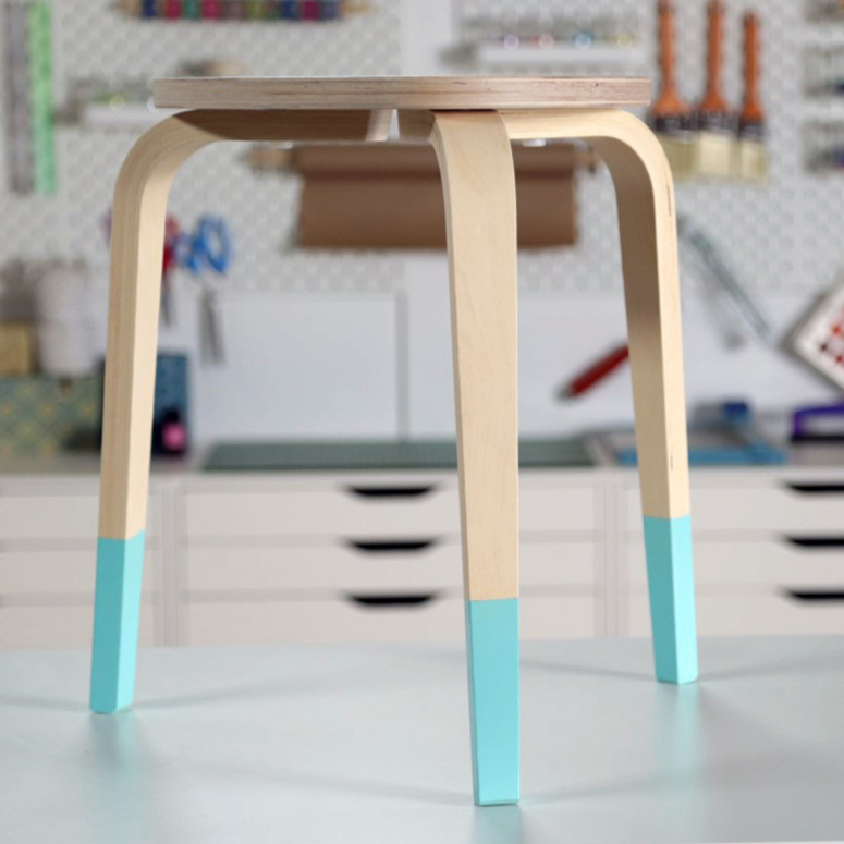 DIY stool designs: The three-legged wooden stool spraypainted a bright turquoise only on the lower third of its legs.