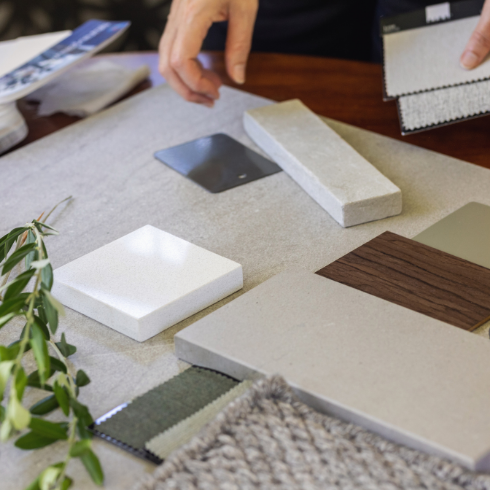 Interior design elements like tile and flooring samples being laid out on a table.