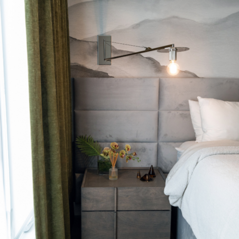 Nightstands with storage drawers flanking the bed; small vases of greenery clippings and little candles in dark brown glass votives sitting atop the nightstand