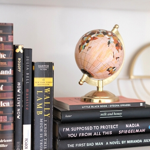 Pink globe and black books on a white bookshelf