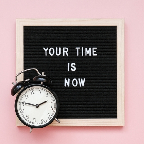 Your time is now. Motivational quote on letter board and black alarm clock on pink background. Top view Flat lay Concept inspirational quote of the day.