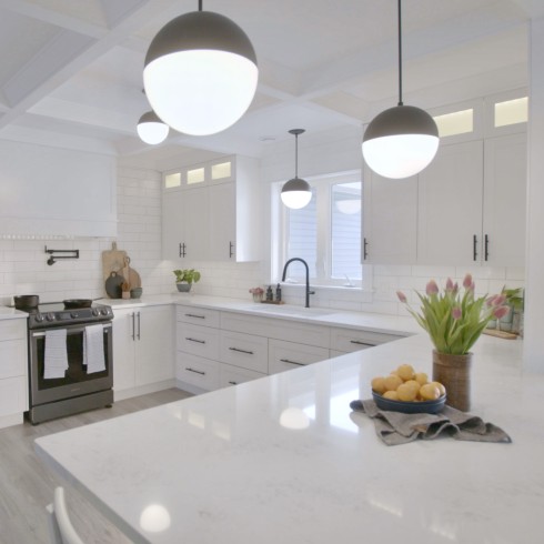 A modern white kitchen with globe pendants