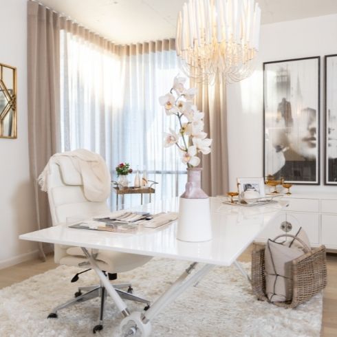 Office with white walls, a white desk, white chair and chandelier