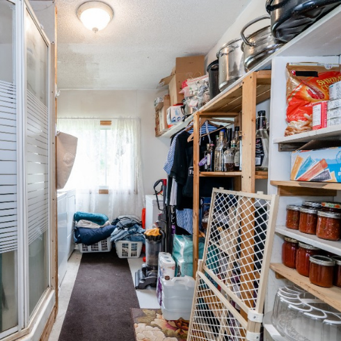 A messy pantry with a shower and washer and dryer
