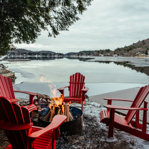 Firepit at the lake surrounded by red patio chairs
