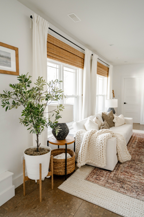 Beneath a white sofa, a rosy Persian-style rug is layered atop a slightly larger white jute rug.