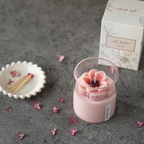 A pink floral candle beside a box and matches.