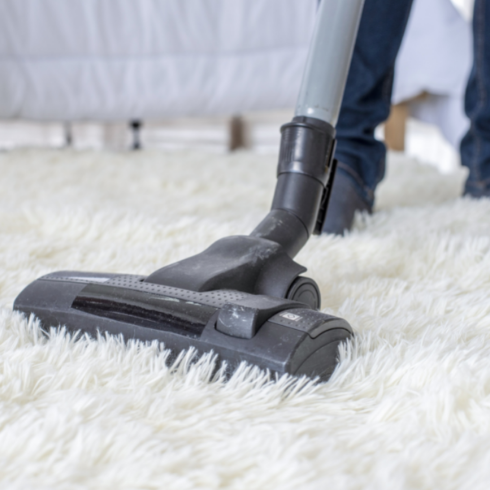 A vacuum running over a white fur rug.