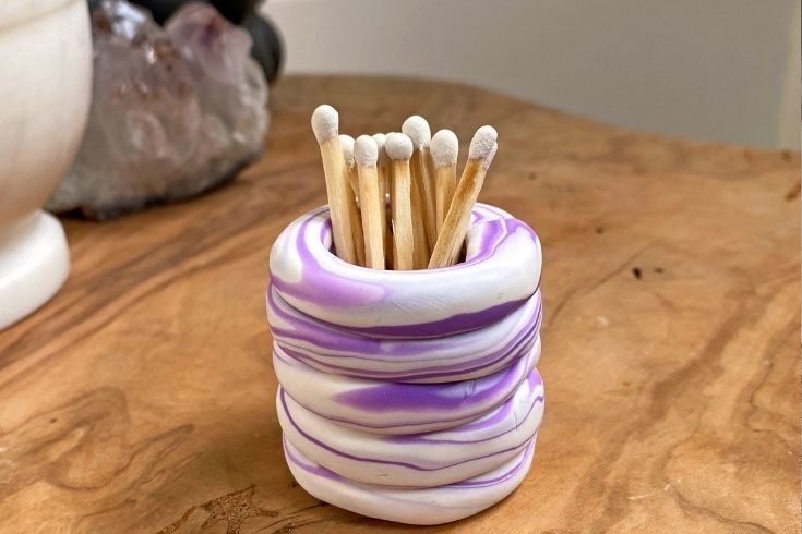 A purple and white match stick holder filled with matches