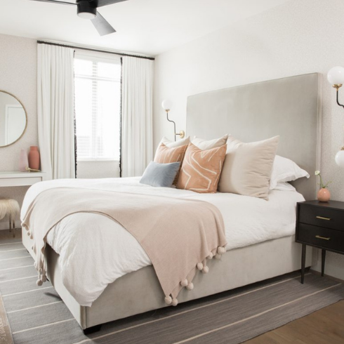 A neutral, clean aesthetic bedroom with a mix of pillows and blankets on white bed