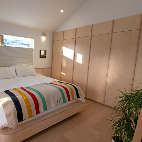 A simple Scandinavian-style bedroom, constructed using lots of wood and sparsely decorated.