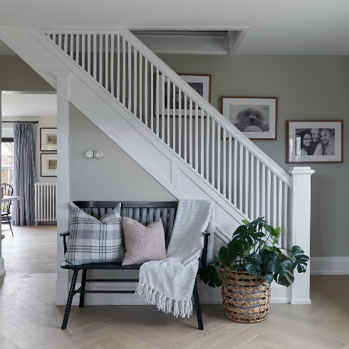 Grey herring bone floors in an entryway with a white staircase and gallery wall