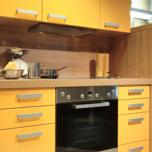 A yellow kitchen with bright yellow upper and lower cabinets with silver hardware.