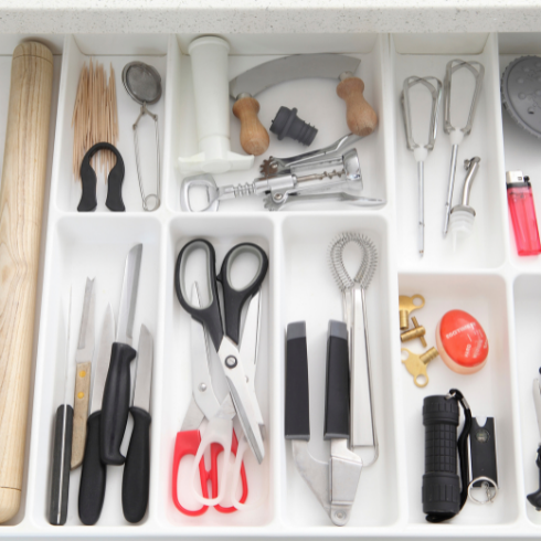 A kitchen drawer perfectly organized with dividers, each segment designated to a specific item or type of item.