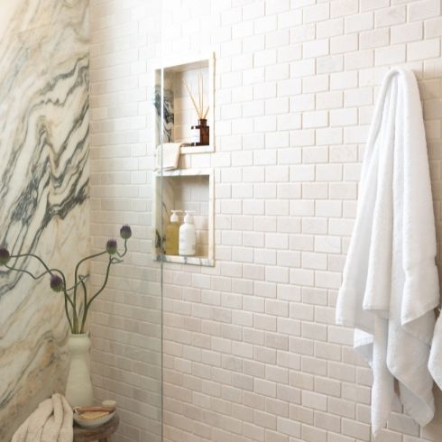 White walk in shower with subway tile and marble feature wall