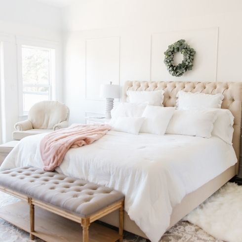 A white room with a pink bed and white bedsheets
