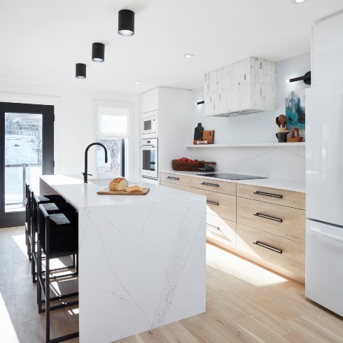 White kitchen with fluted marble range hood and wood cabinetry