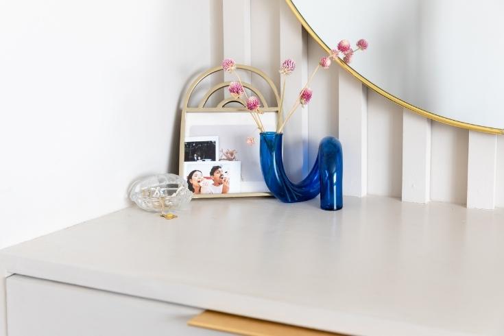 Retro abstract vase with dainty pink flowers and portraits displayed on a dresser