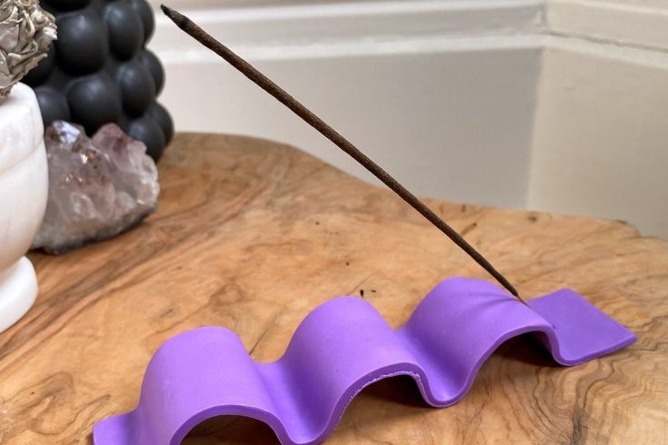 Wavy purple incense holder with an incense stick