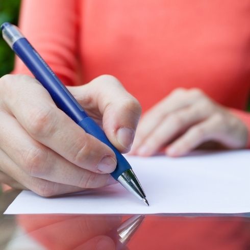 A woman writing in a guest book with a pen