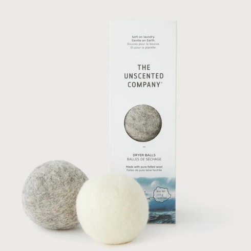 A tall, skinny white box of dryer balls with two dryer balls - one grey and one white - sitting in front of it.