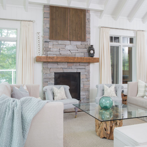 A living room with cream toned love seats, pale blue chairs and a pastel blue throw blanket