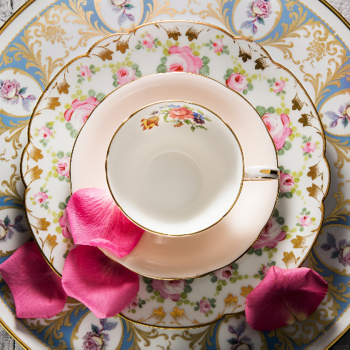 A mix and match vintage China place setting with a stacked dinner plate, side plate, saucer and teacup.