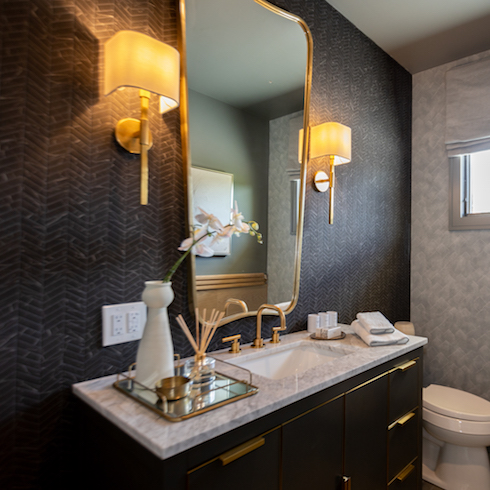 Sleek cabana bathroom with dark walls and gold accents