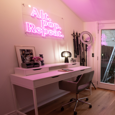 Office desk with pink neon sign hanging overhead
