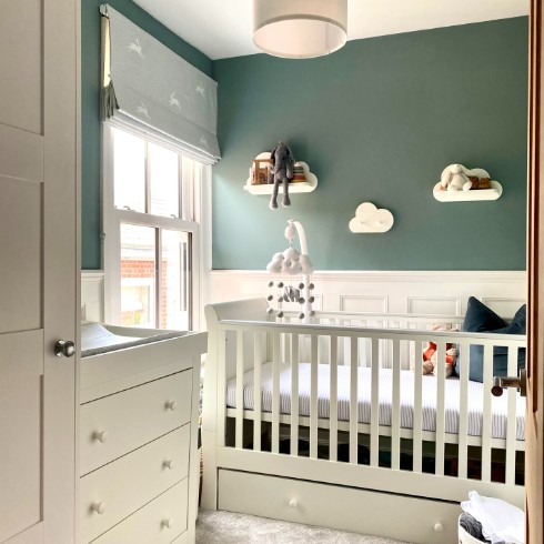 Green nursery with white crib and white cloud shelves