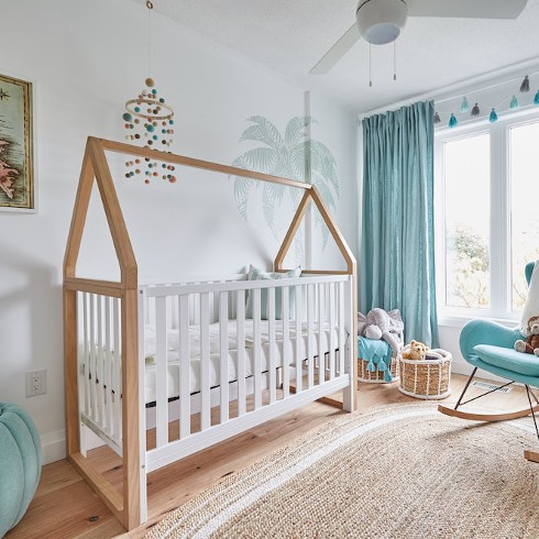 White nursery with house-shaped crib and blue curtains