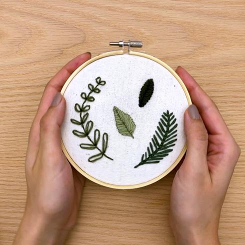 Embroidery hoop with different embroidered leaves.