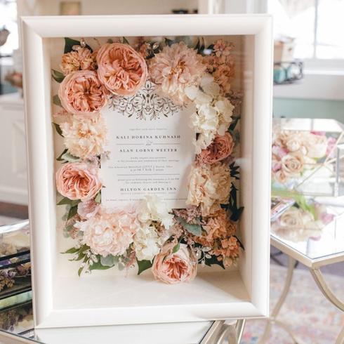 A memory box filled with flowers and a wedding invitation.