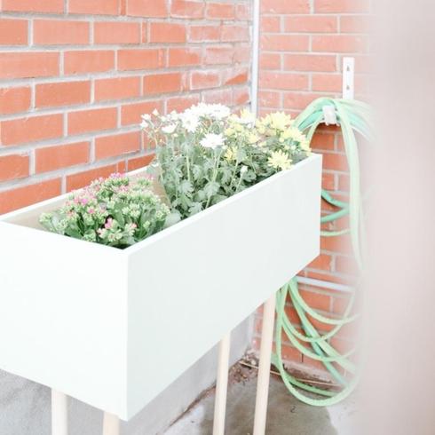 White planter box on a porch with flowers.
