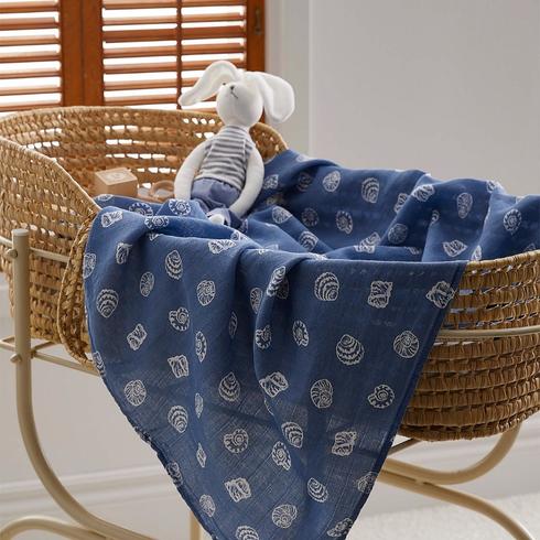 Rattan bassinet with blue seashell printed muslin blanket.