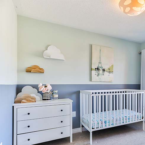 Nursery with blue and green walls, white crib, white dresser.