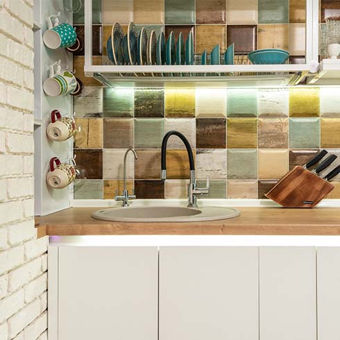 A kitchen with faux distressed tiles and white cabinets.