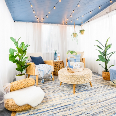 Bright blue and white sun room with boho chic furniture and tall decorative plants